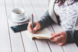 איך כותבים הצעת מחיר - אישה שכותבת בכתב יד בתוך מחברת